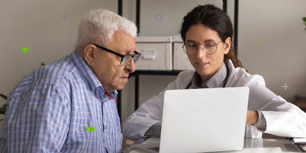 Paciente masculino de edad avanzada escucha a su doctora mientras ven una computadora