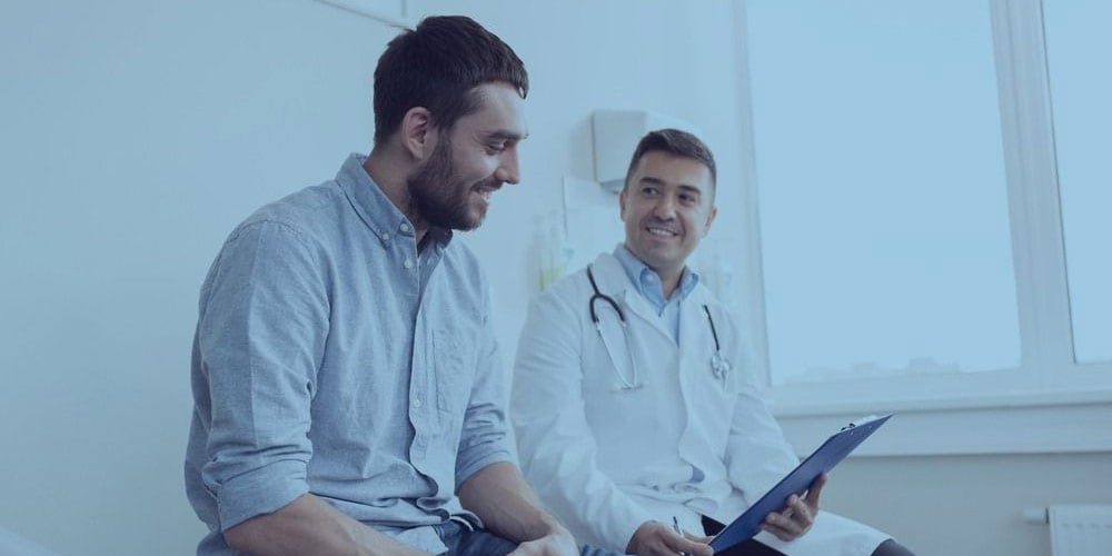 Um médico mostrando um documento para seu paciente sentado um ao lado do outro sorrindo
