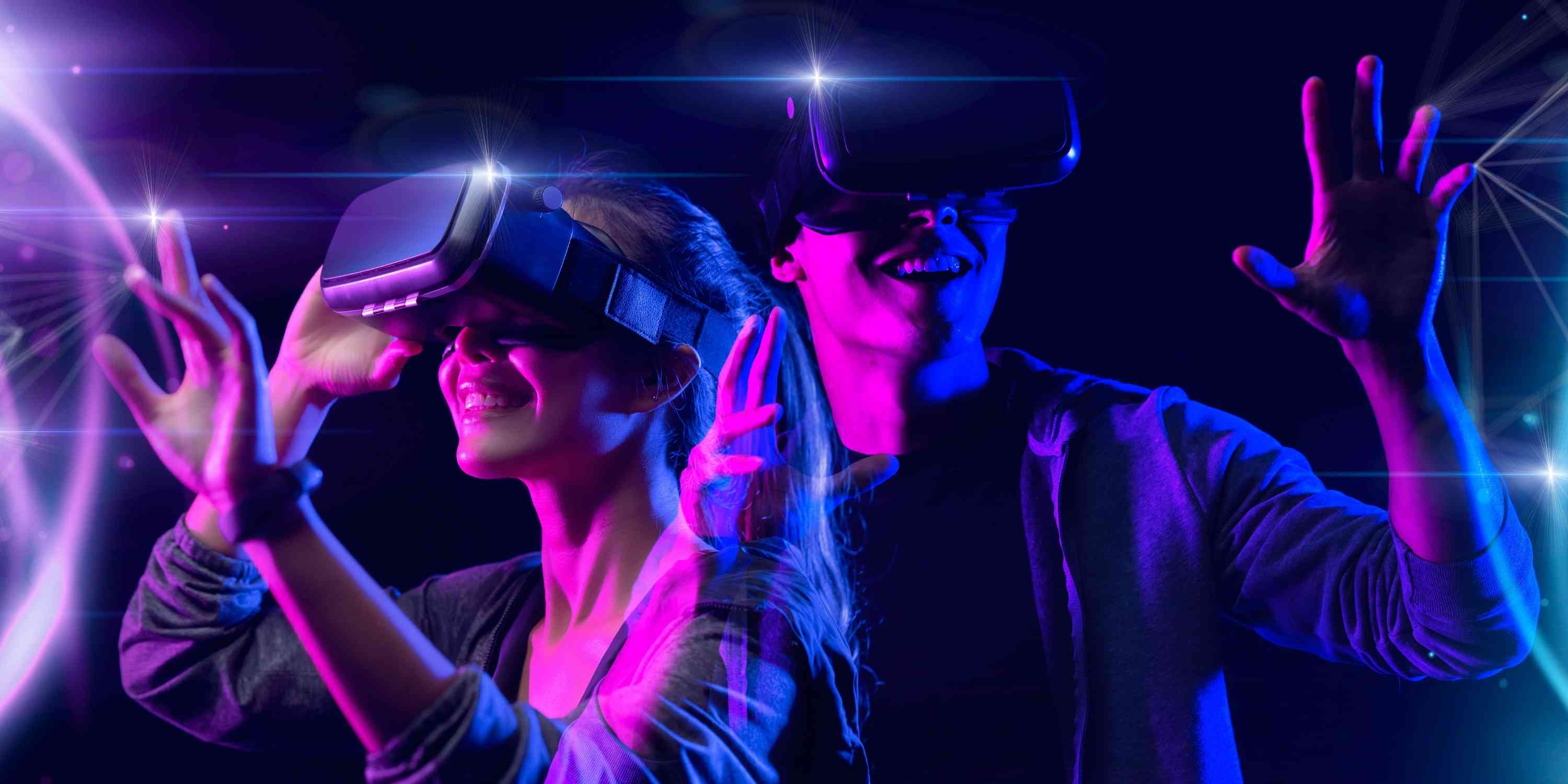 Two people smile wearing virtual reality headsets.